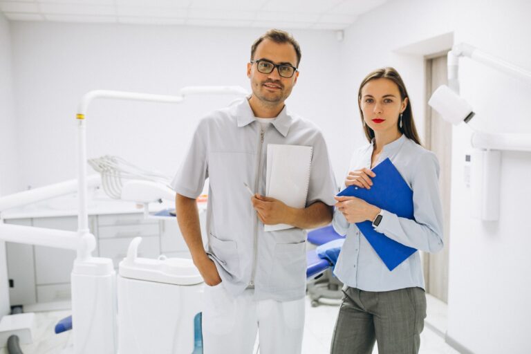 Dentista pode ser MEI? Dentistas em pé, a frente da cadeira odontológica fazendo pose para a foto.