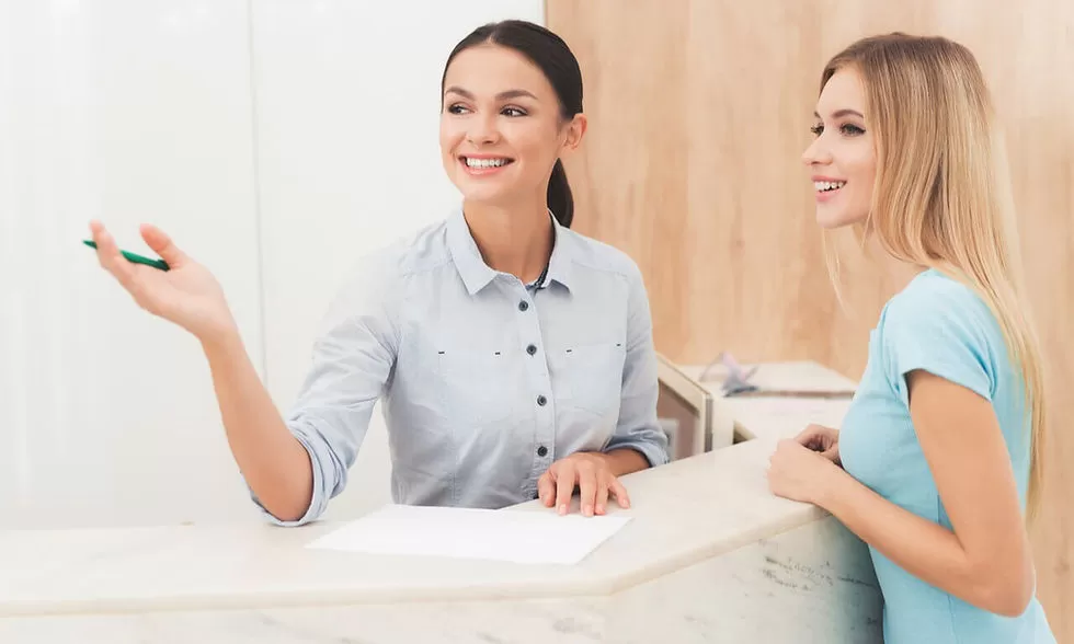 Recepção de clínica de estética. Doutora dentista conversa com a paciente na recepção de clínica de estética.