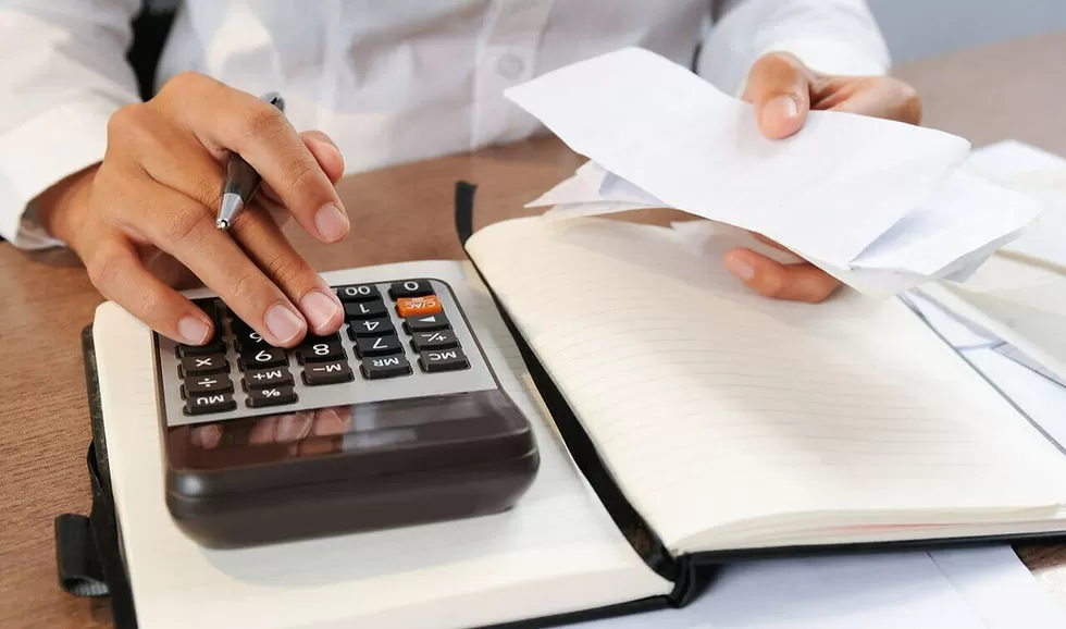 Como emitir nota fiscal. Foto com foco no gestor mexendo na calculadora e fazendo a emissão da nota fiscal.