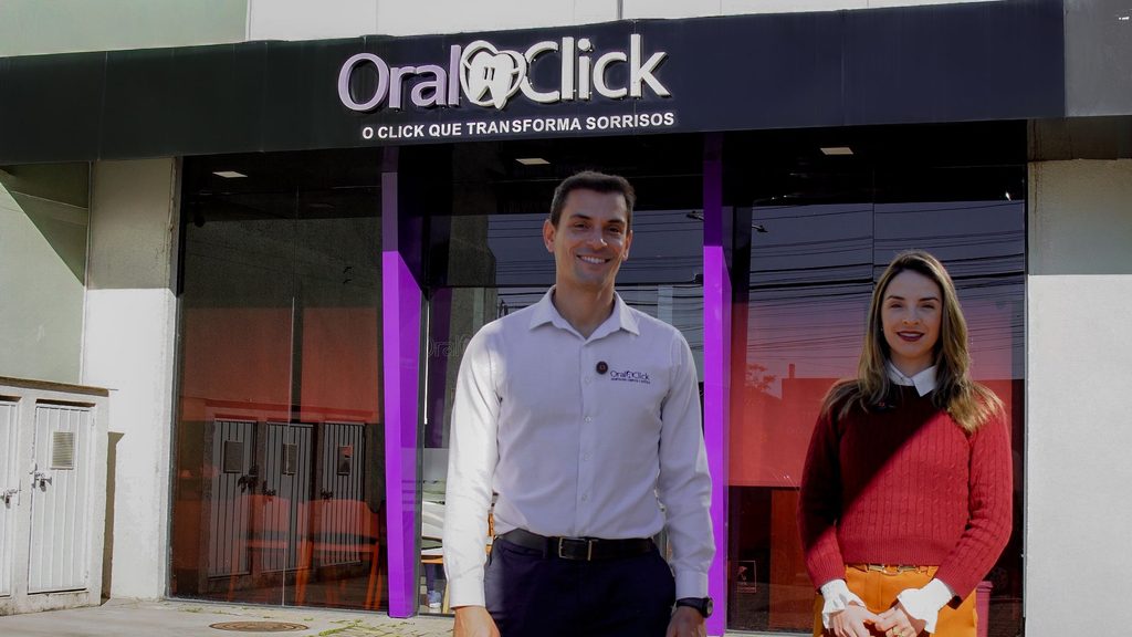 História de Clientes: Dra. Mariana e Eduardo em frente a clínica Oral Click.