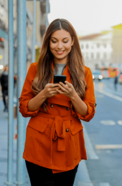 melhor software odontológico e de estética. mulher andando na rua e usando celular
